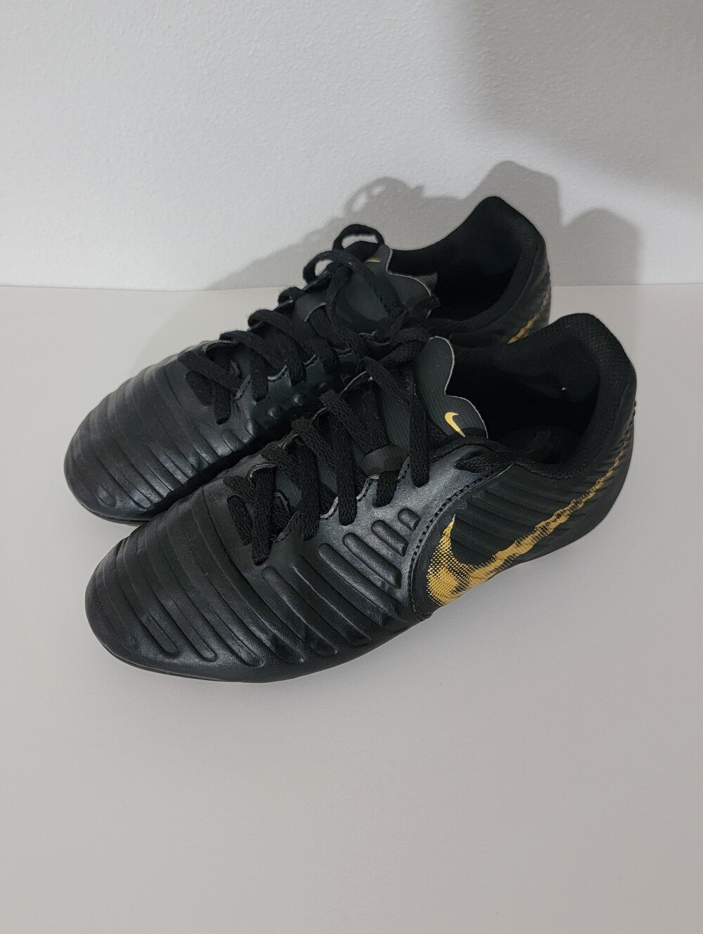 Nike Tiempo Legend 7 Club soccer cleats in a black and metallic gold colorway